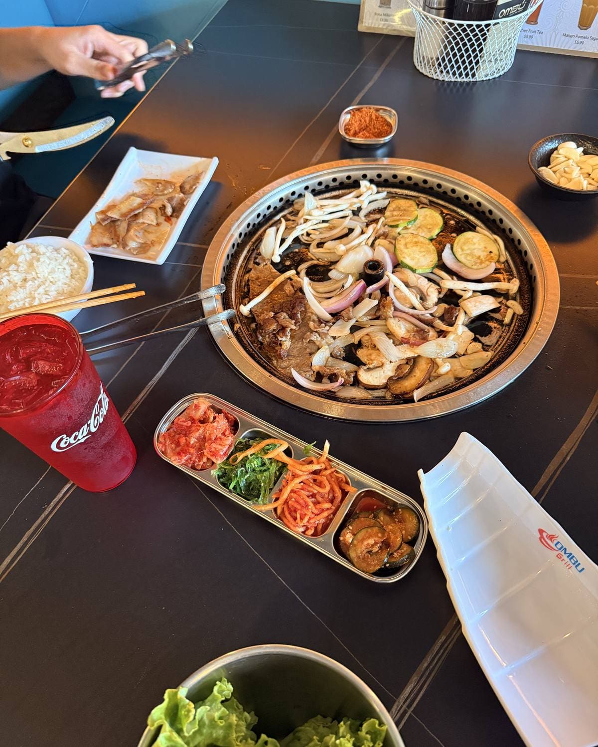 Table-side Korean BBQ grill with meats, vegetables and banchan at Ombu Grill